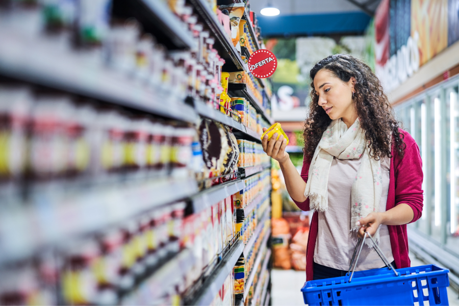Woman holding soup can in grocery aisle with basket, protected by BDI consumer packaged goods insurance