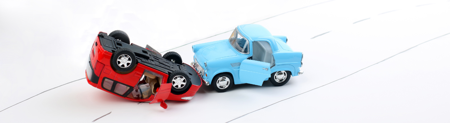 Two toy cars crashed and one is flipped over representing a car wreck for uninsured motorist coverage insurance