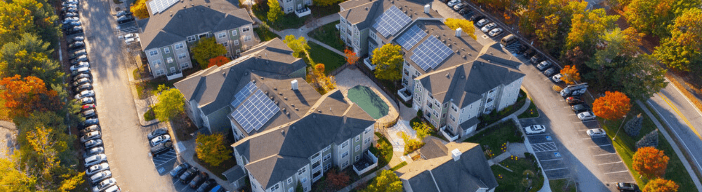 Aerial view of apartment complex with solar panels on rooftops.